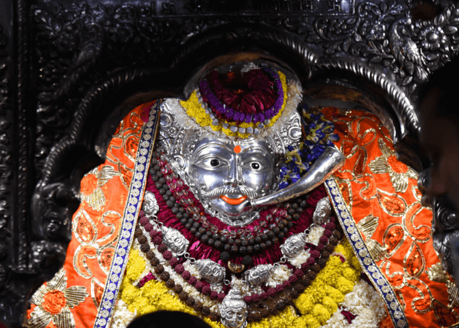 The silver face of Baba Kal Bhairav adorned with garlands and sacred ornaments