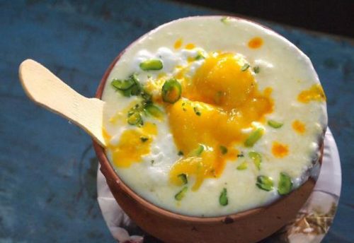 A clay cup of lassi topped with saffron and pistachios, a Varanasi favourite