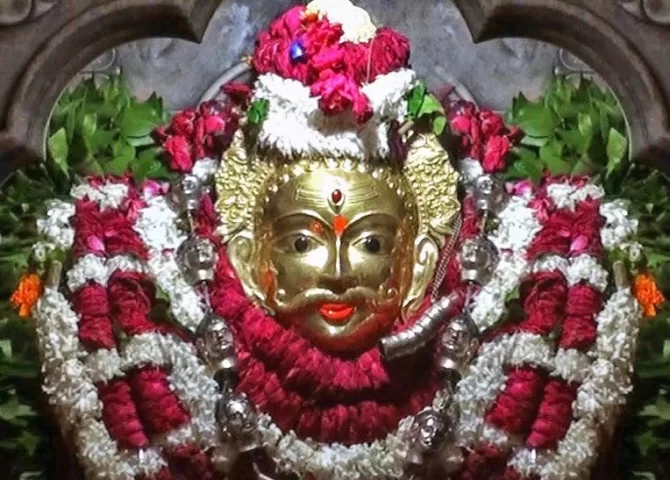 The golden face of Kal Bhairav surrounded by flower garlands in Varanasi