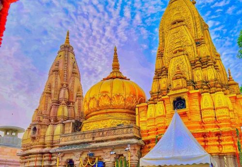 The golden spire and dome of the Kashi Vishwanath Temple with devotees in the queue